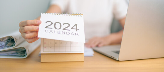 2024 Year Calendar on table with business woman using laptop computer. countdown, Happy New Year, Resolution, Goals, Plan,  Action, Mission and financial Concept