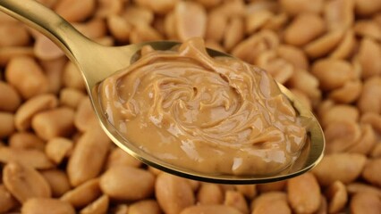 Wall Mural - Peanut butter in golden spoon and peanuts on background