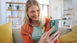 © Azeemud/peopleimages.com - Woman, smartphone typing and laugh on sofa in home, reading social media and app. Face of happy gen z girl scroll on cellphone for funny meme, download mobile games and search network in living room