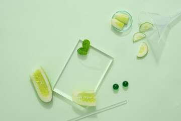 Wall Mural - Some fresh cucumber slices decorated with transparent podium on green background. Blank space for display cosmetic product of cucumber extract, reducing sebum, helping to prevent acne from developing