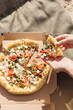 © Westend61 - Hands of woman holding pizza slice on sunny day