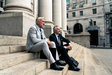 Thoughtful Businessman Sitting With Colleague On Steps