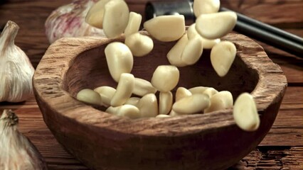 Poster - Peeled garlic falls into a wooden plate. Filmed on a high-speed camera at 1000 fps. High quality FullHD footage