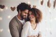 A beautiful young couple hugs and smiles in a bright room.