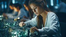 A Female Electrical Engineer In A White Lab Coat Is Performing An Optical Check On PCB Boards While Working On An Electronic Assembly Line..