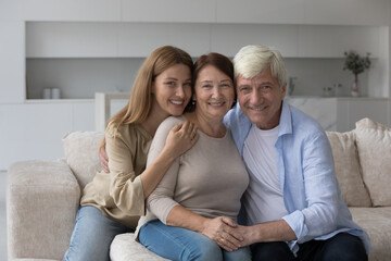 Wall Mural - Happy senior woman enjoying warm good relationship with adult daughter and loving older husband, posing with family for shooting, looking away, smiling, laughing