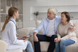 © fizkes - Young doctor visiting happy mature older couple of patients at home, talking to positive husband and wife, explaining prescription, telling good examination news, giving medical consultation