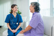 © kelvn - Asian young nurse taking care and talking mature female patient sitting on sofa in hospital. Healthcare concept.
