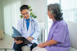 © kelvn - Mature male doctor taking care and talking mature female patient sitting on sofa in hospital. Healthcare concept.