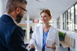 © Halfpoint - Pharmaceutical sales representative shaking hand with female doctor in medical building. Hospital director consulting with healthcare staff.