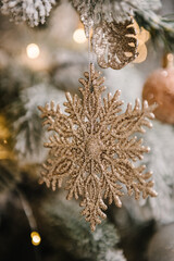 Wall Mural - Golden snowflake and shiny Christmas decorations and glittering toys on Christmas tree. Fir-tree decorated with garlands. Happy New Year and Merry Christmas. Decor and interior decoration. Closeup.