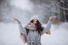 Happy active girl having fun and throwing snow in winter forest