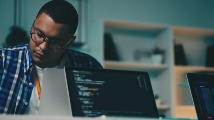 African American software tester checking computer programs on laptop in office