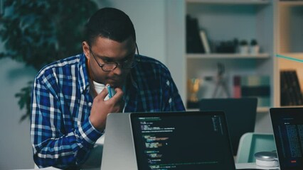 African American software developer testing program on laptop and writing notes
