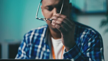 African American programmer feeling eyestrain during work, taking off glasses