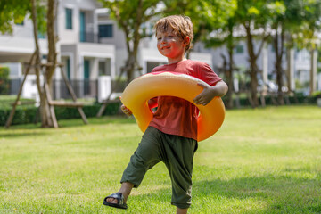 Wall Mural - Portrait of a boy smiling happily and laughing outdoors with a blurred green park background on a sunny day.