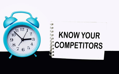Wall Mural - view of a notepad with the text know your competitors, clock on a black and white background. busine