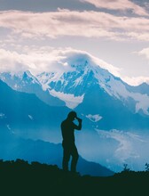 a person standing in front of snow capped mountains holding a camera