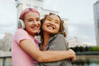 Two smiling girls hugging while standing at city street