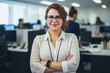 © SOLDATOOFF - Portrait of a cheerful brown-haired woman with glasses on office background.