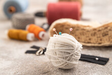 Sewing accessories: scissors, thread, thimbles, braid on brown concrete background. Side view, selective focus