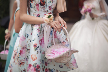 Little bridesmaid with a basket of rose petals. Girls holding rose petals at the wedding ceremony. romantic moment, decoration concept. happy joyful wedding celebration event. 