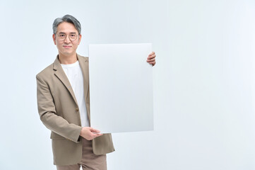 A middle-aged man in a suit and glasses is holding a white sign and making various facial expressions and gestures.