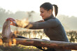 Sporty athletic young woman doing stretching exercises on a cold sunny morning in autumn
