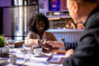 © Marko Geber - Smiling woman making handshake with partner in sushi restaurant