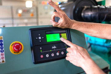 Close-up of the hands of a man operating a control panel in a factory