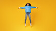 © Prostock-studio - Shocked lady with open arms jumps on yellow background, full length