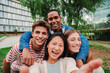 © Jose Calsina - Group of young multiracial high school students taking a selfie portrait picture outside with a toothy smile looking at camera laughing and having fun together. Happy friendly teens shooting a photo