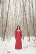 © Milou Dirks - asian young woman in long red dress standing in white snow landscape in forest