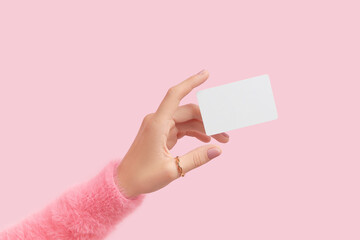 Womans hand touch a white blank business card that floats on a pink background. Flat lay of a simple business card with top view