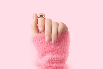 Poster - Beautiful groomed womans hand with pink matte nail design on a pink background. Manicure, pedicure beauty salon. 