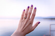 Woman's hand with a proposal diamond ring by the sea, sunrise on beach proposal, white sapphire golden ring