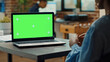 © DC Studio - Woman checking green screen display in startup office, looking at isolated chroma key template. Female employee using blank copyspace and mockup on laptop, business coworking space.