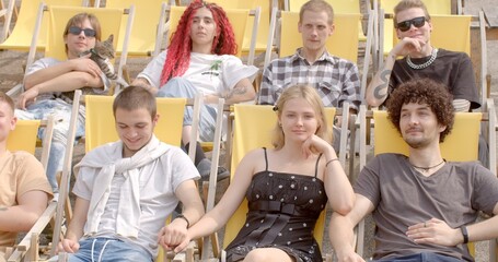 Celebrating differences. Young people sitting, talking on yellow chairs after lectures. Portrait of contemporary youth depicts bold generation. Being authentic in world that celebrates uniqueness.