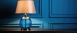 A trendy color scheme for your interior includes a blue lampshade and a table lamp with a glass element near a light wall all complemented by a grey cloth