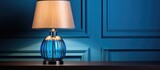 Fototapeta Mapy - A trendy color scheme for your interior includes a blue lampshade and a table lamp with a glass element near a light wall all complemented by a grey cloth
