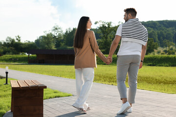 Wall Mural - Romantic date. Beautiful couple walking in park on sunny day, back view