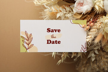 Wall Mural - Beautiful card with Save the Date phrase and dry flowers on beige background, top view