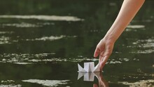 Woman Put Paper Chip On Water In The Park Close Up. Origami Paper Crane On A Pond. Natural Lake View On Sunny Day. 