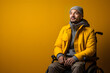 © Patcharaphon - Portrait of happy adult disable man with prosthetic leg sitting on wheelchair. Smiling handicapped young guy on yellow background. Studio shot, copy space. Generative Ai, illustration