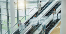 Business People, Elevator And Travel With Office And International Trip With Lens Flare. Corporate, Professional On Escalator And Appointment With Conference, Stairs For Convention And Executives