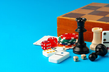 Items for playing chess, poker and domino on blue background studio shot