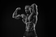 © andy_gin - Silhouette of a strong bodybuilder. Confident young fitness athlete with a powerful body and perfect abs. Black and white photography. Dramatic light.