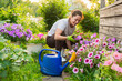© Юлия Завалишина - Gardening and agriculture concept. Young woman farm worker gardening flowers in garden. Gardener planting flowers for bouquet. Summer gardening work. Girl gardening at home in backyard