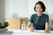 © DragonImages - Portrait of female entrepreneur filling application form when working at office desk