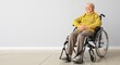 Senior woman in wheelchair near light wall with space for text
